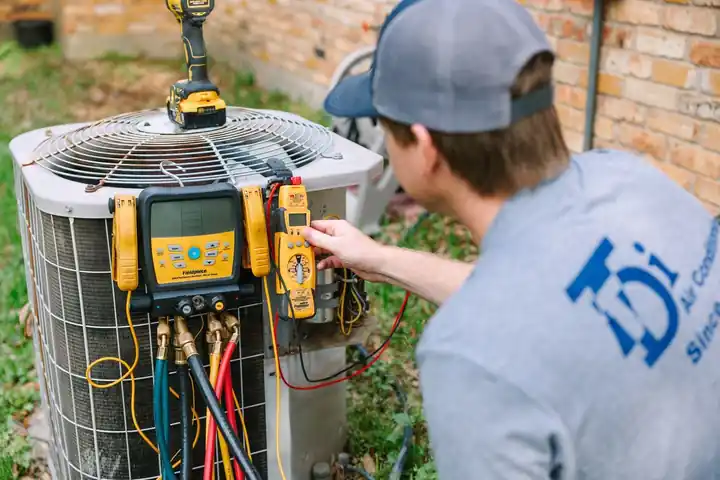 TDi technician reading manifold gauges on a residential condenser
