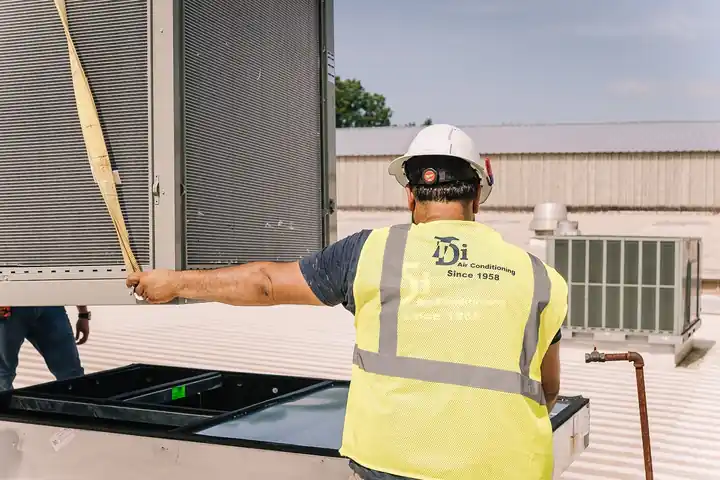 TDi technician from behind on a metal roof, vest reading Since 1958