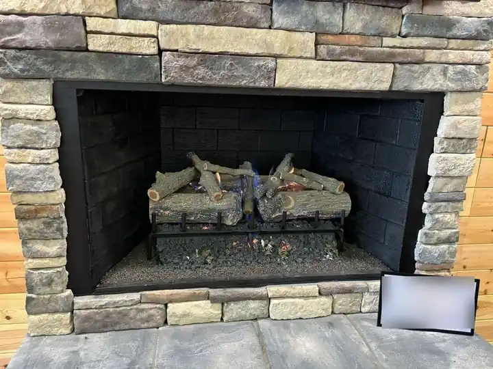 A stacked-stone gas log fireplace on display in the Tyler showroom
