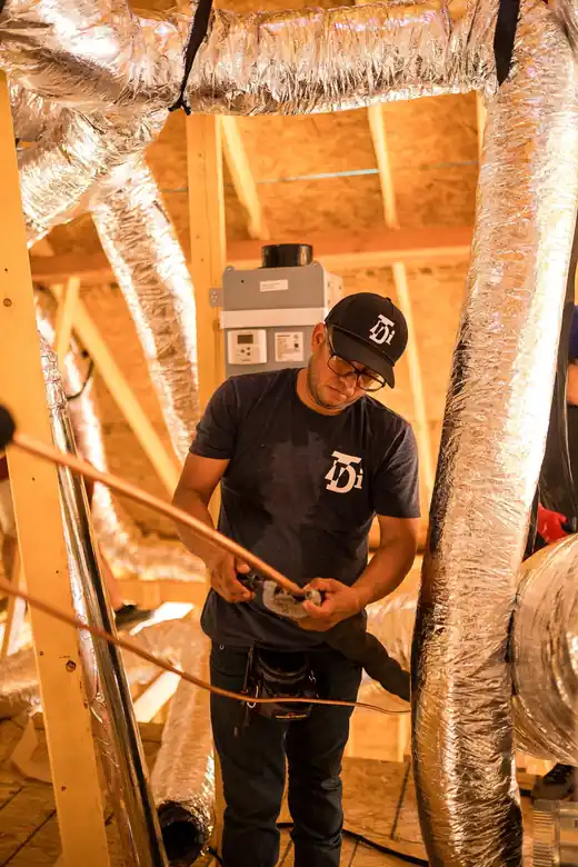 TDi technician in a new-build attic among flexible ductwork