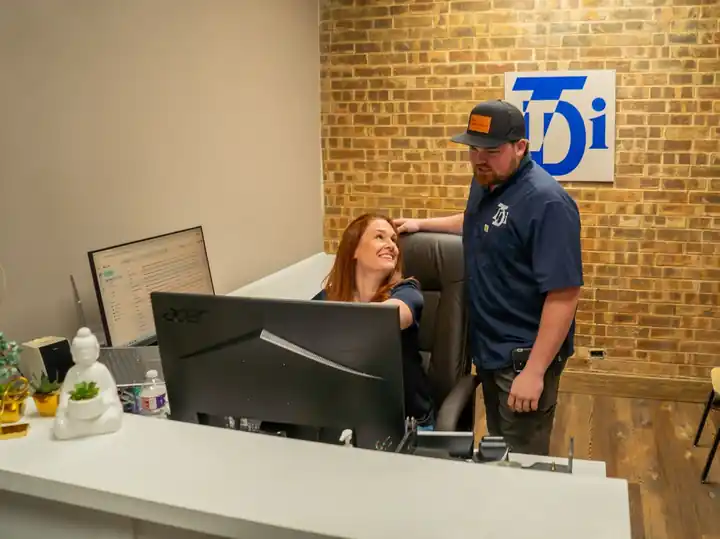 TDi staff at the front desk beneath the TDi wall logo
